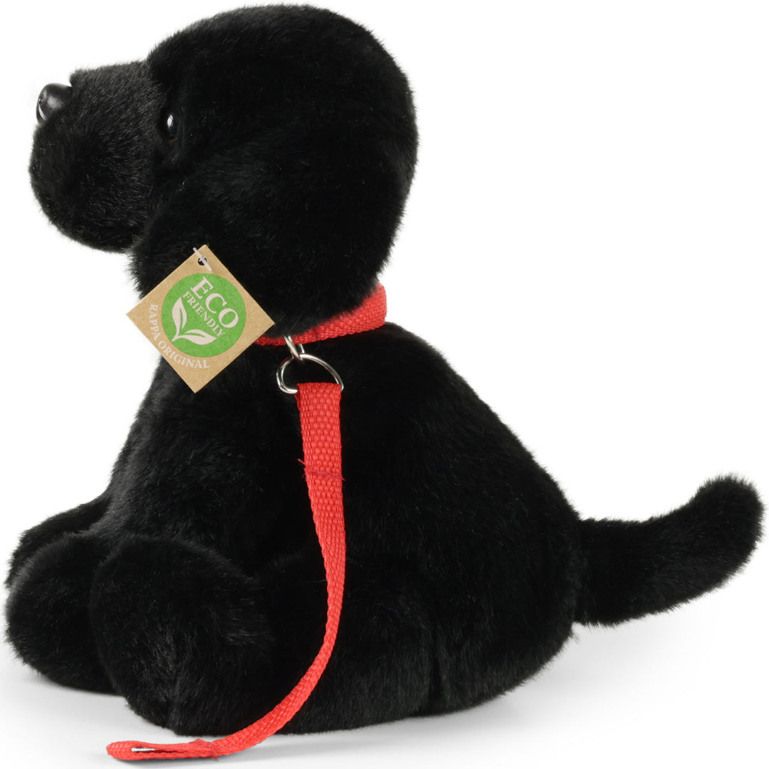 Rappa pluchen Labrador hond met rode halsband en riem, schuin van achteren gefotografeerd.