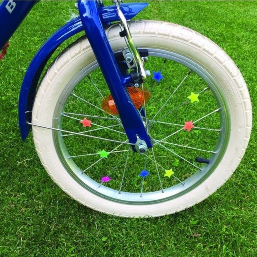 Fietswiel met veelkleurige ster-spaakdecoratie op het gras.