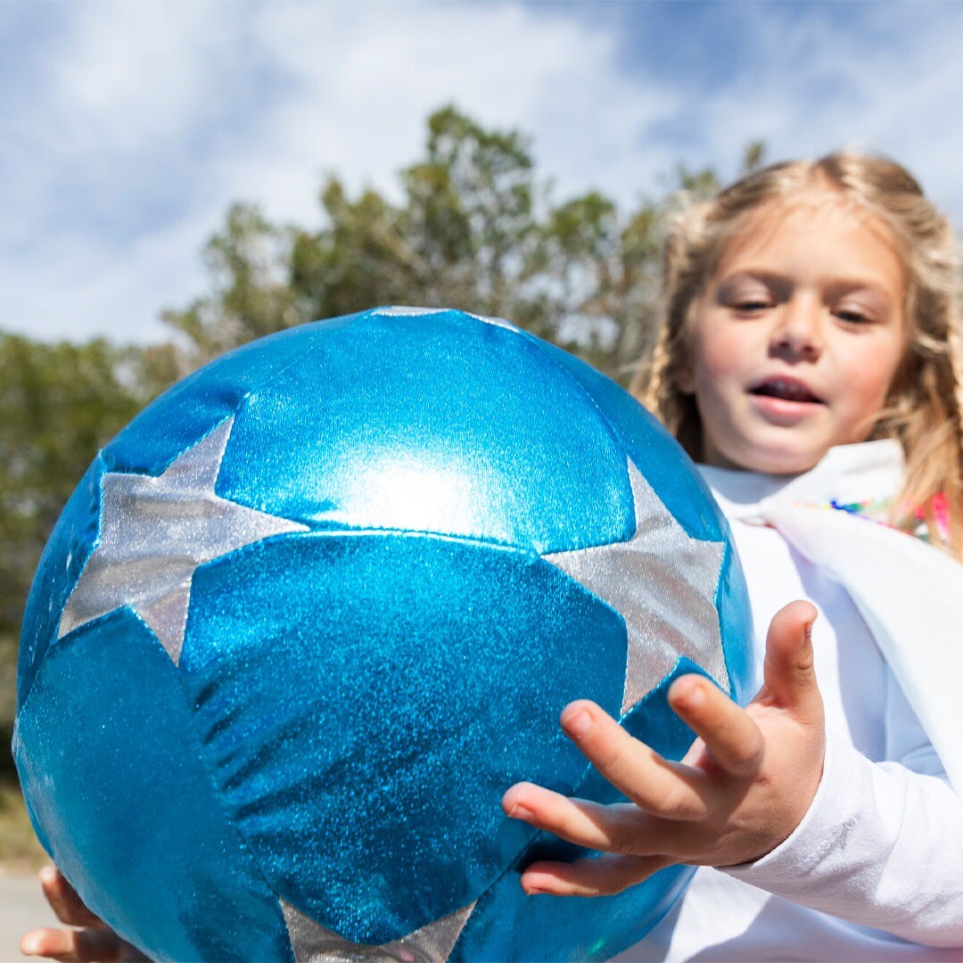 Een meisje houdt een blauwe ratatam speelbal met sterren vast.