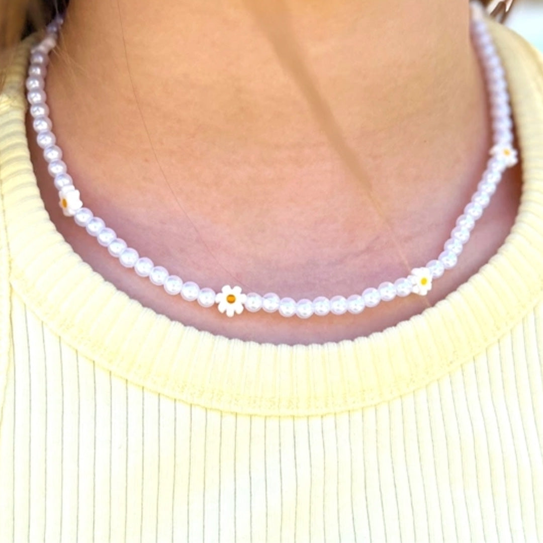 Een kind draagt de Ratatam kinder kralenketting met madeliefjes.
