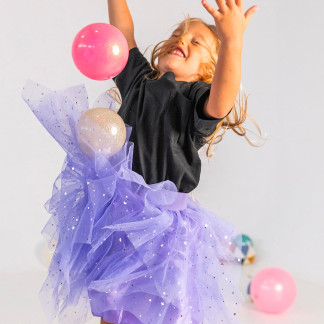 Lachend meisje springt en gooit een Ratatam roze glitter speelbal in de lucht.