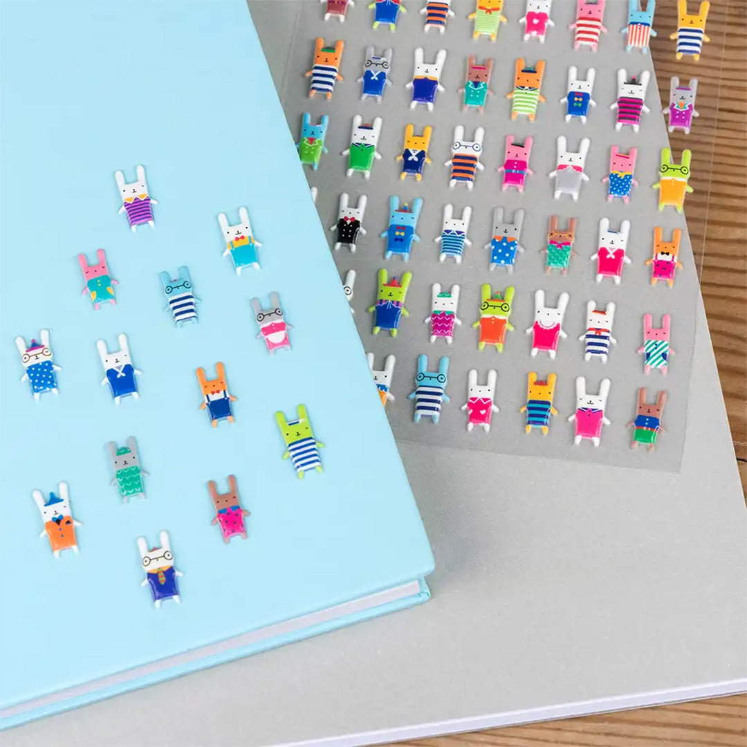 Veelkleurige 3D stickers van konijntjesfiguren, deels geplakt op een blauw notitieboek.