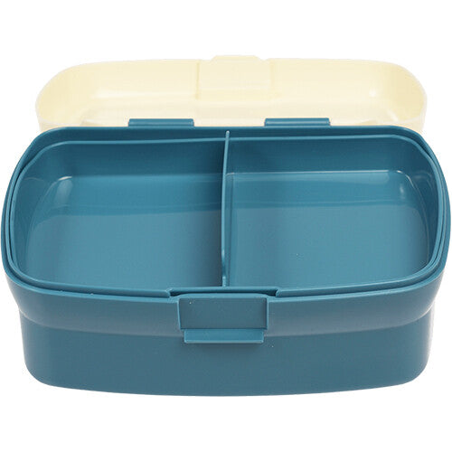 Open Rex London plastic broodtrommel met blauwe onderkant en crèmekleurige deksel, met het vakjesblad in de onderkant.