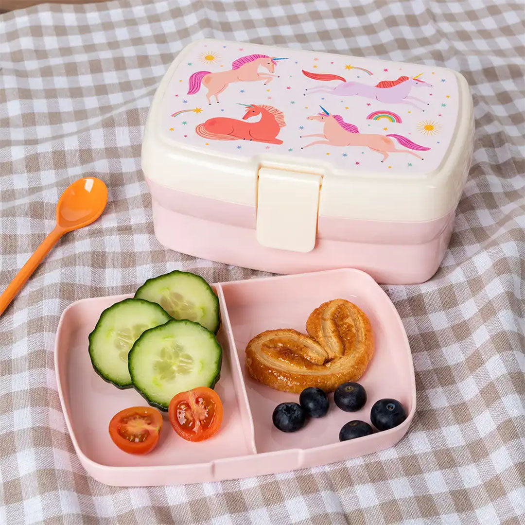 Rex London kinderbroodtrommel met eenhoornfiguren en een open vakjesblad gevuld met fruit en groenten.