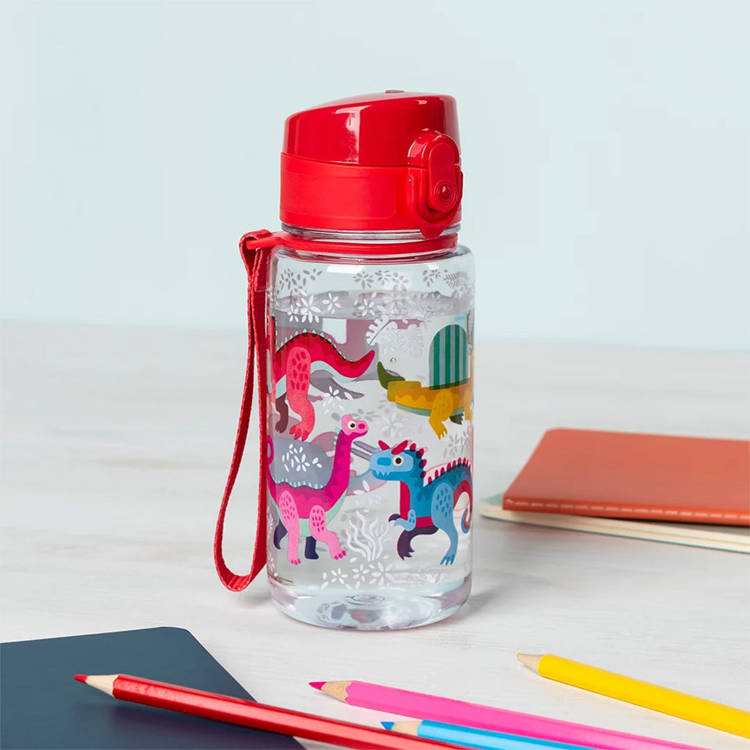 Rex London drinkfles voor kinderen met dinosaurusprint op een bureau met schrijfwaren.