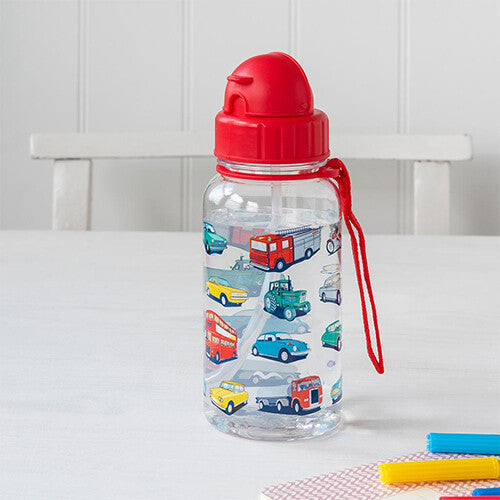 Rex London kinder drinkfles met voertuigpatroon en rood rietje, staand op een tafel.