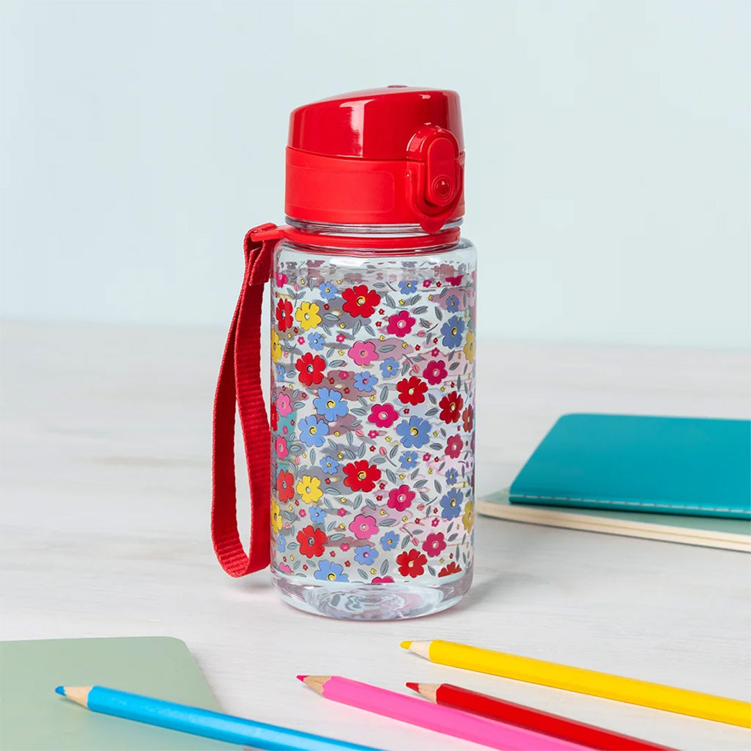 Rex London kinder drinkfles met bloemenpatroon op een bureau met kleurpotloden.