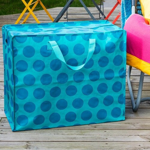Rex London jumbo opbergtas van plastic, groen met blauwe stippen, staand op een houten vlonder.