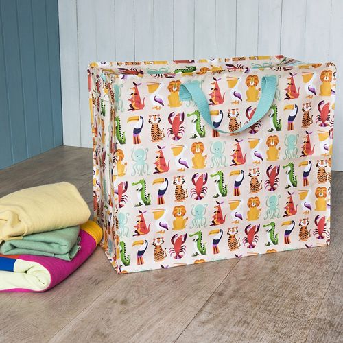 Rex London jumbo opbergtas met kleurrijk dierenpatroon op een houten vloer, met opgevouwen kleding ernaast.