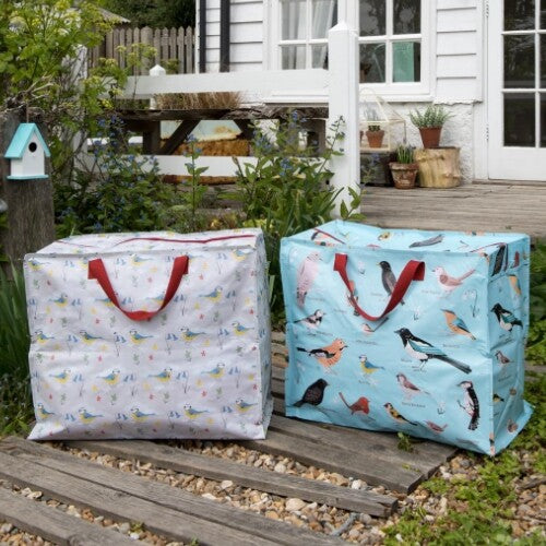 Twee Rex London jumbo opbergtassen met vogelpatronen, staand op een houten terras buiten.