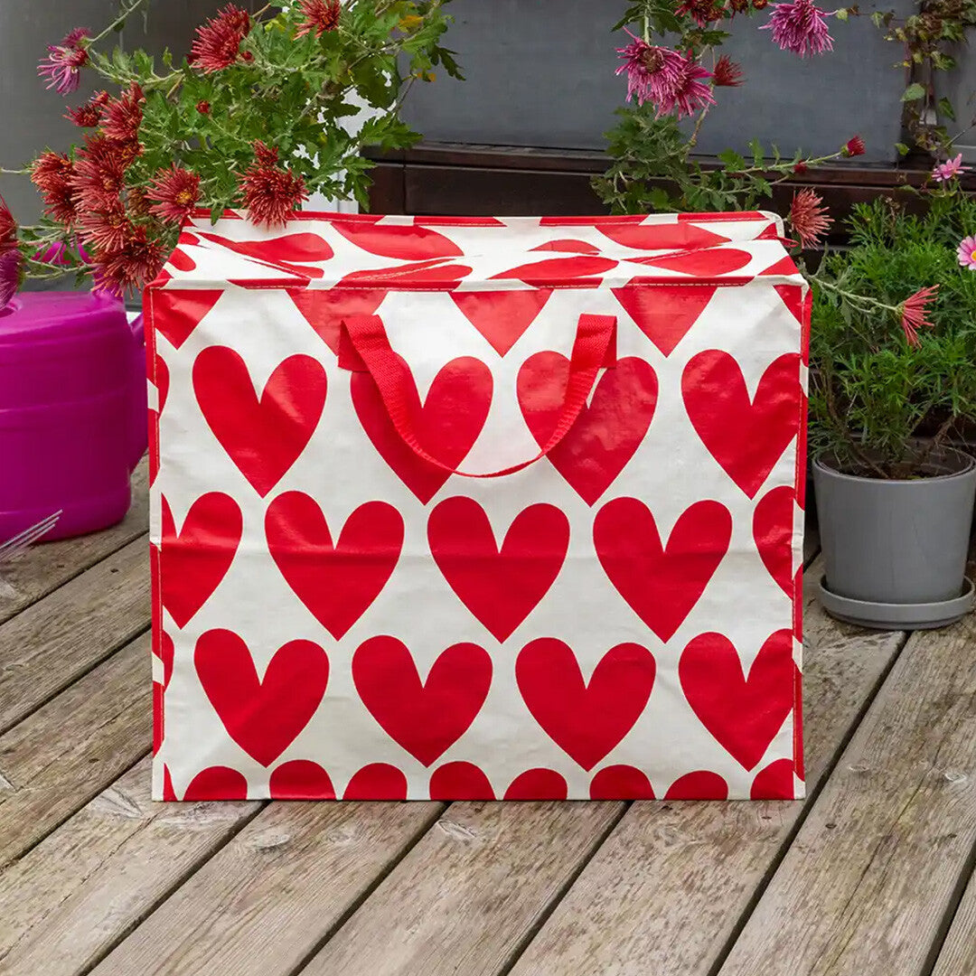 Rex London jumbo opbergtas met rood hartenpatroon, staand op een houten terras.