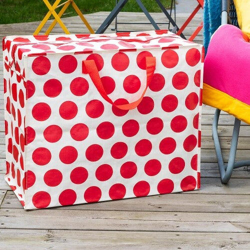 Rex London jumbo opbergtas met rode stippen op een houten terras.