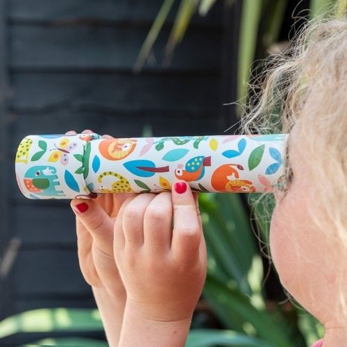 Een kind kijkt door de Rex London Wild Wonders caleidoscoop met dieren- en bladerenpatroon.