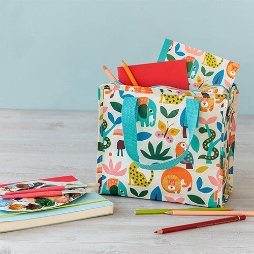 Rex London kindertas met wild wonders dierenpatroon, gevuld met kleurpotloden en een notitieboek, op een houten tafel met kunstbenodigdheden.