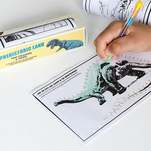 Een kind kleurt een dinosaurus op de Rex London Prehistoric Land kleurplaten en spelletjes op rol met een veelkleurig potlood.