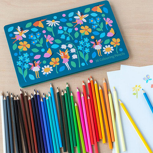 Rex London blikken doos met feeën en bloemen, omringd door losse kleurpotloden en tekenpapier op een houten tafel.