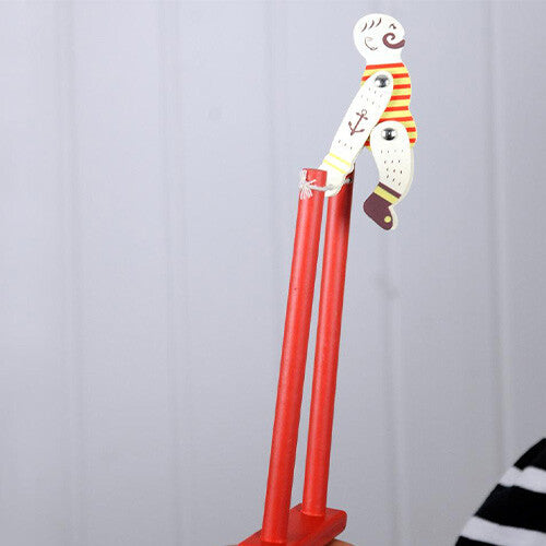 Rex London houten knijpspeeltje acrobaat Mr Muscular staat rechtop op een rood frame, vastgehouden door een hand.
