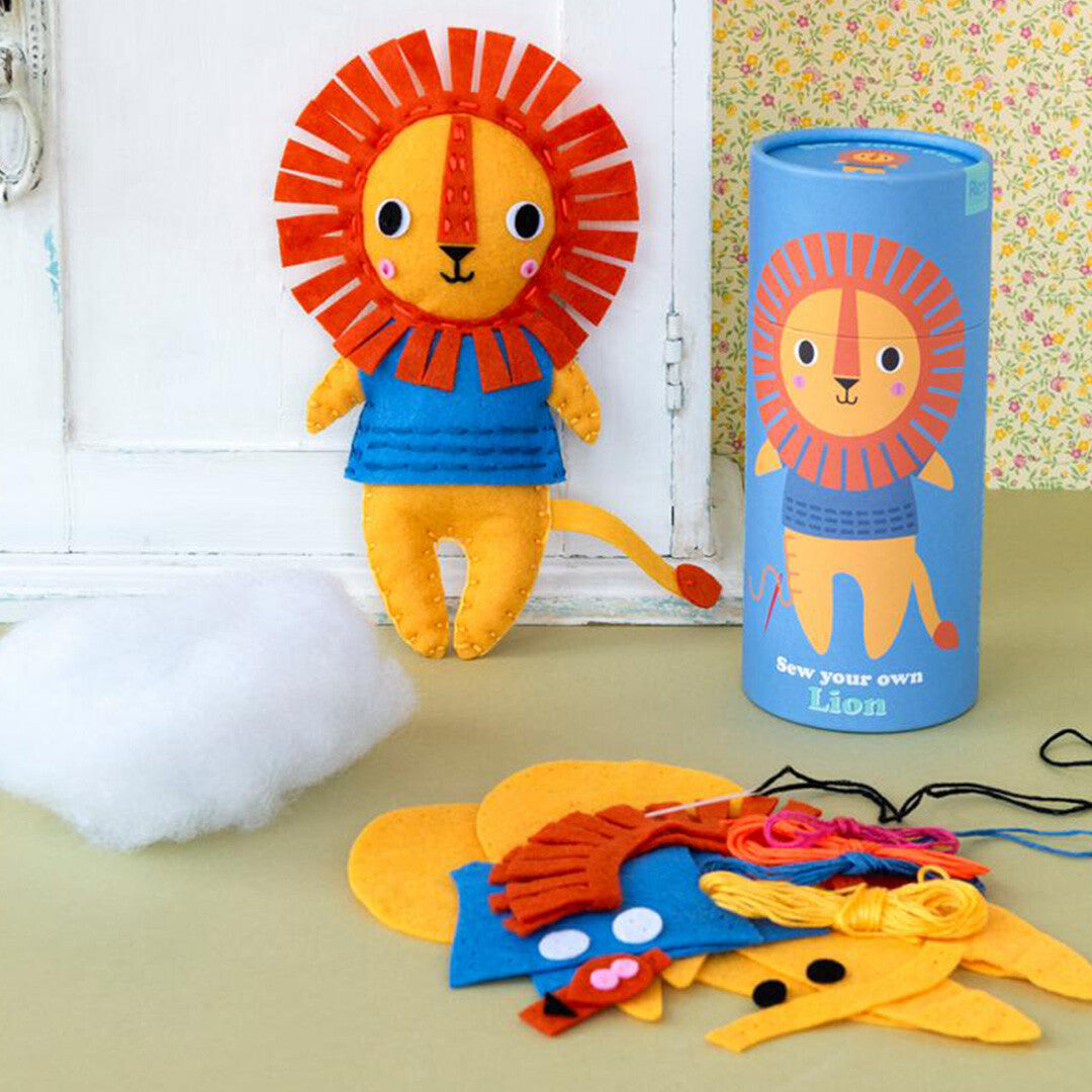Rex London knutselpakket voor kinderen met een vilten leeuw, de verpakking en de losse onderdelen op een tafel.