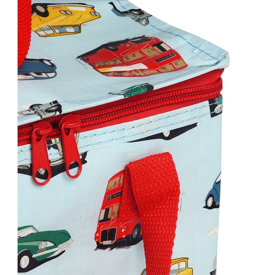Detail van de rode rits en handvat van de lunchtas met voertuigpatroon.