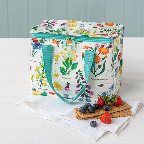 Kinderlunchtas met wild flowers patroon op tafel naast fruit en crackers.