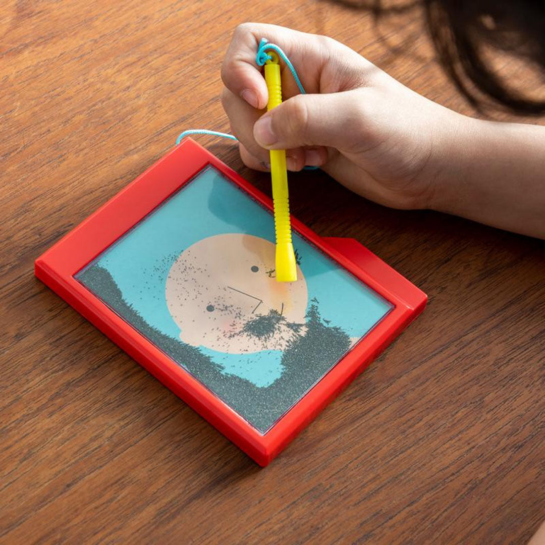 Een kind tekent met een gele magnetische pen op het Fuzzy Face magneetspel.
