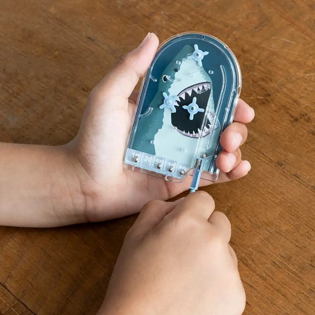 Kinderhanden spelen met de Rex London mini flipperkast met haai-thema.