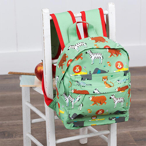 Rex London mini rugzak met dierenparkprint hangend aan een witte stoel, met een appel ernaast.