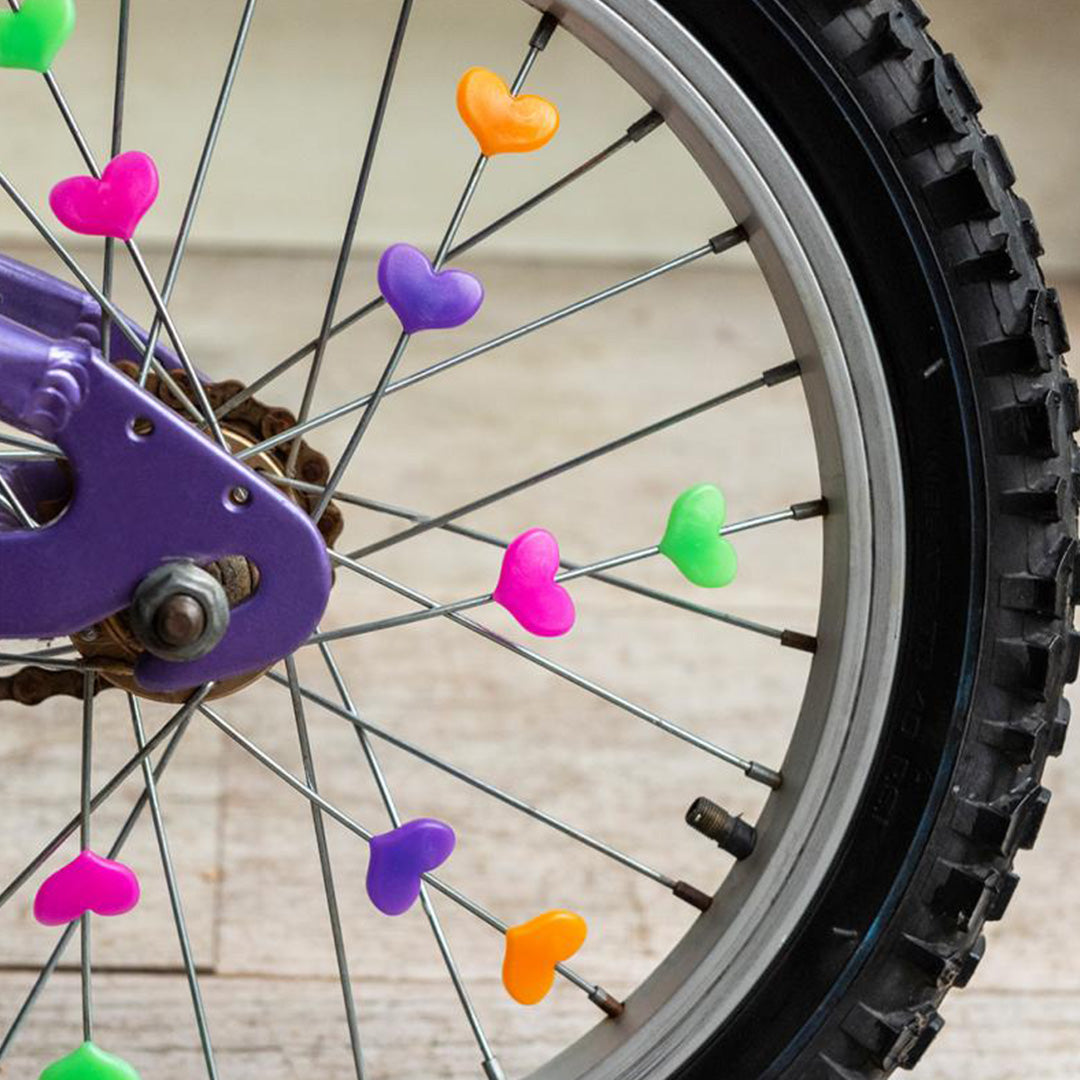 Gekleurde hartjes spaakdecoratie van Rex London bevestigd aan de spaken van een fietswiel.