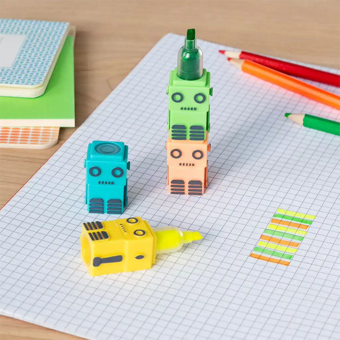 Drie Rex London robot highlighters gestapeld op een schrift, met een gele highlighter die een gemarkeerde streep toont.
