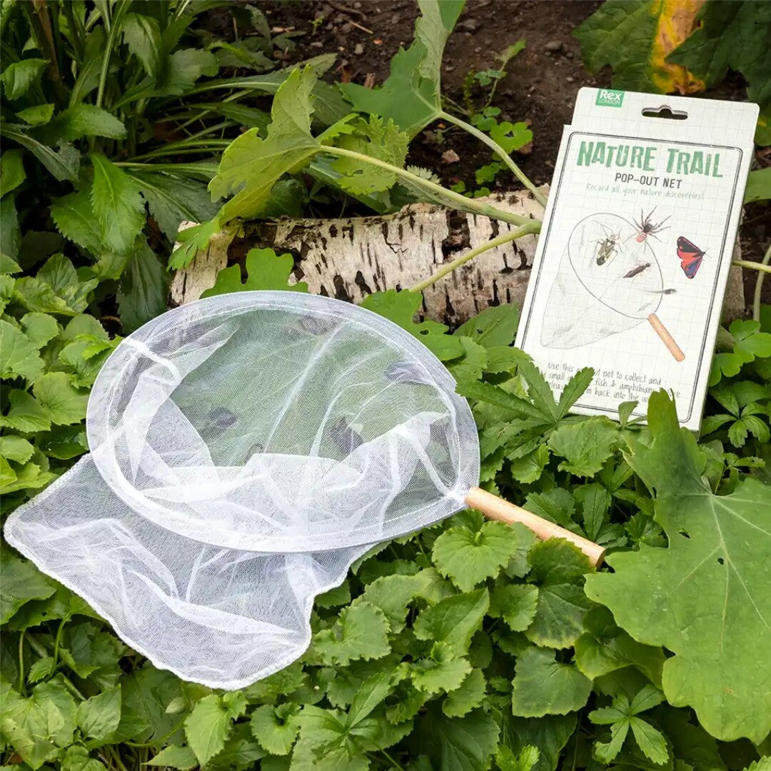 Het Rex London uitklapbare schepnetje en de verpakking liggen tussen groene planten.