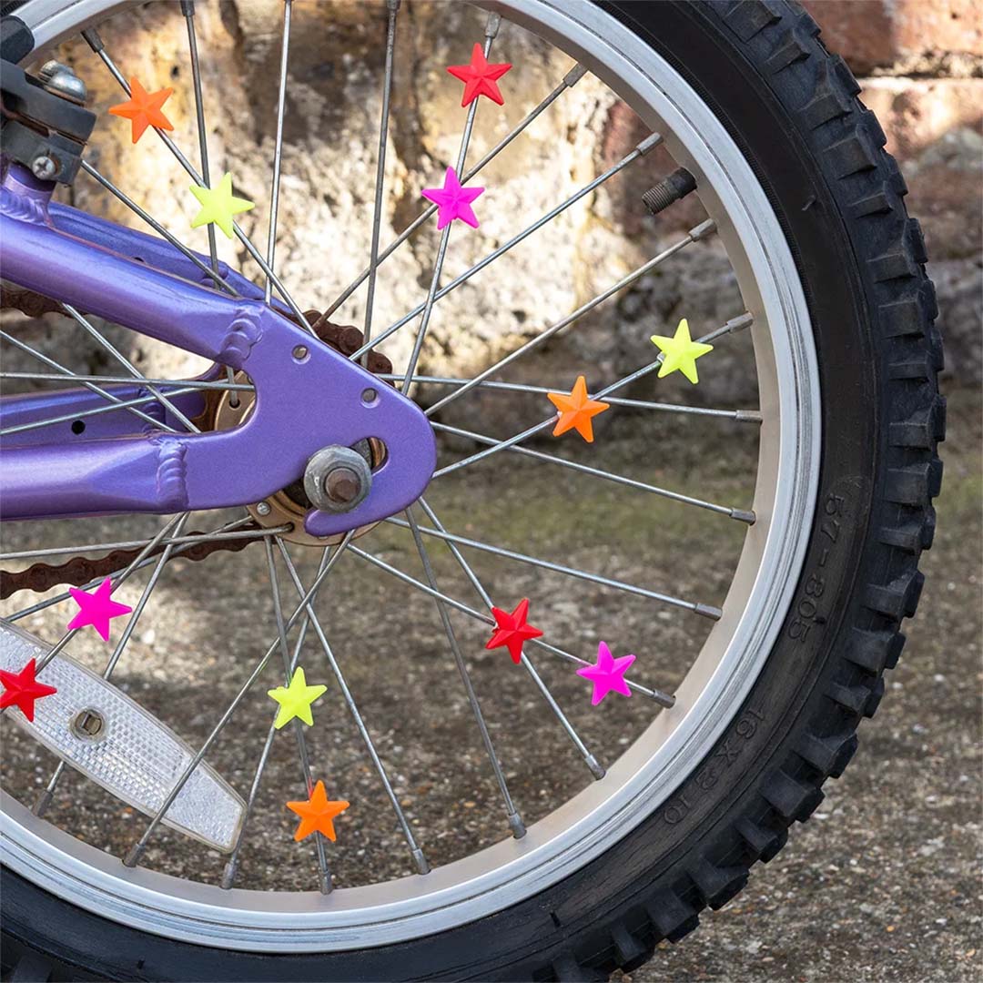 Veelkleurige sterren spaakdecoratie bevestigd aan de spaken van een paars fietswiel.