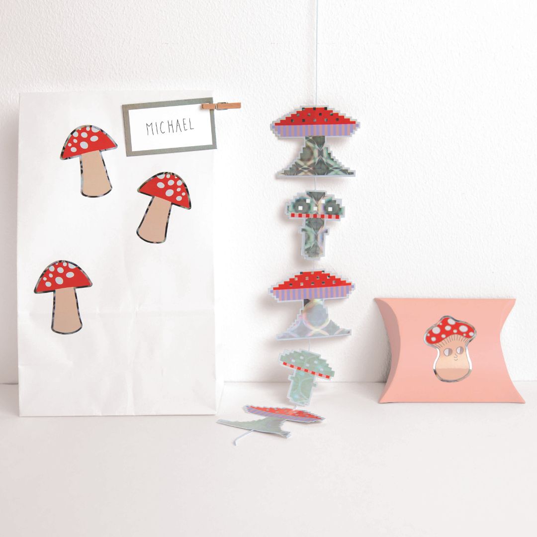 Diverse paddenstoelen stickers gebruikt als decoratie op een papieren zak en een hangende slinger.