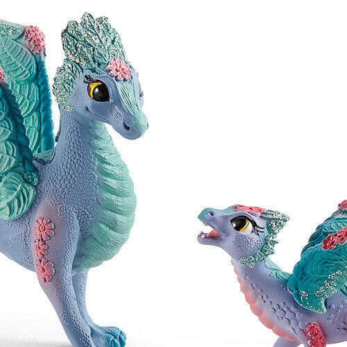 Detailfoto van de koppen van de Schleich Bayala bloemendraak en baby, met glittermanen en roze bloemenpatronen.