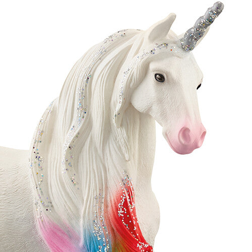 Detailopname van de kop van het witte eenhoorn dierenfiguurtje met regenboogkleurige manen en glitter.