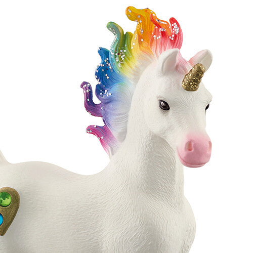 Detailfoto van de kop van het Schleich eenhoorn veulen met regenboogmanen en gouden hoorn.