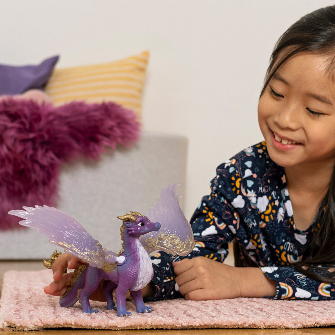 Een kind speelt op een roze kleed met de Schleich bayala sterrenhemel draak.