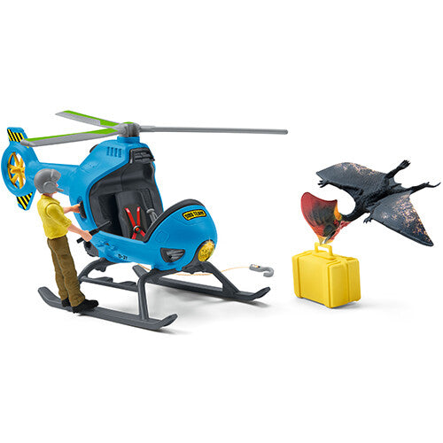 Schleich dinosaurusspeelset met blauwe helikopter, een figuur en een Pteranodon naast een gele kist.
