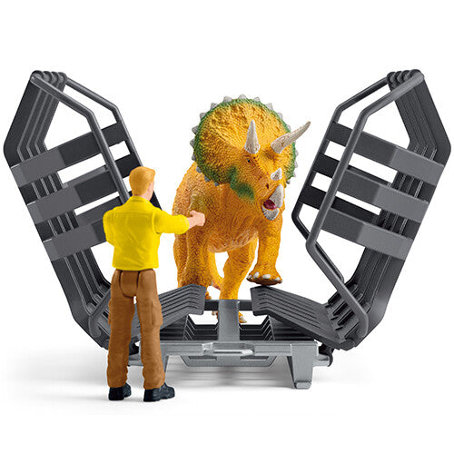 Schleich triceratops figuur in een open grijze kooi met een mannelijke figuur ervoor.