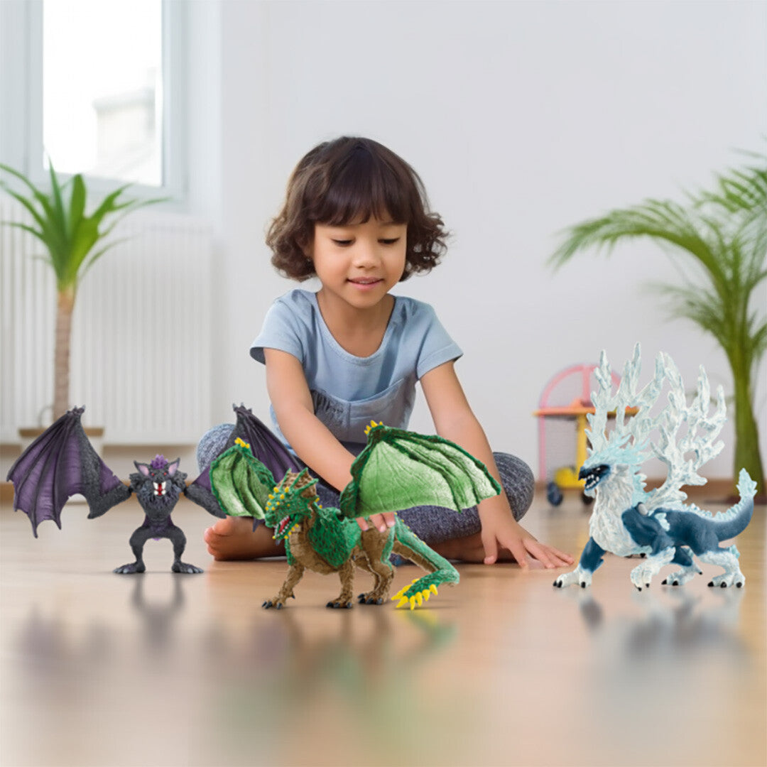 Een kind speelt op de vloer met drie draken speelgoedfiguren, waaronder de blauw-witte ijsdraak.