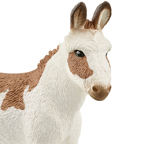 Detailopname van de kop en voorzijde van het Schleich speelgoedfiguurtje van een gevlekte ezel.