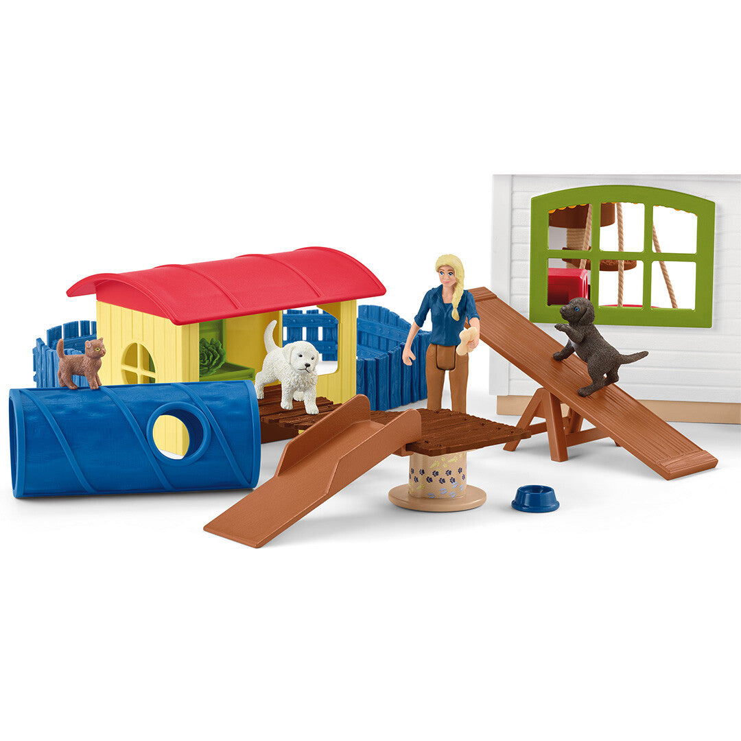 Detail van de Schleich dierenhotel speelset met een mensfiguur, honden, een kat, een tunnel en diverse speelhellingen.