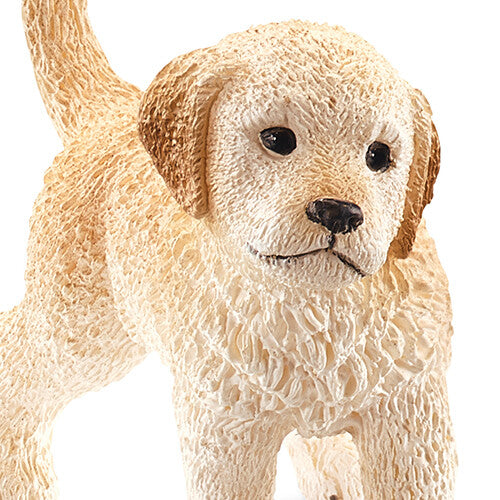 Detailfoto van het Schleich dierenfiguurtje van een golden retriever pup, met focus op de kop en voorpoten.