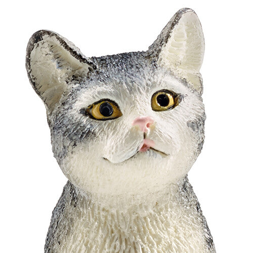 Detailopname van de kop van het grijze gestreepte kattenfiguurtje met gele ogen.