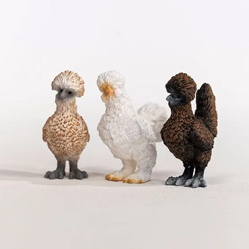 Drie schleich kippen dierenfiguurtjes, een lichtbruine, een witte en een donkerbruine, staan naast elkaar.