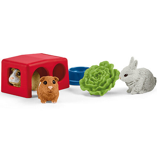 Detail van de Schleich speelset met een rood huisje, twee cavia's, een konijn, een blauwe voerbak en een krop sla.