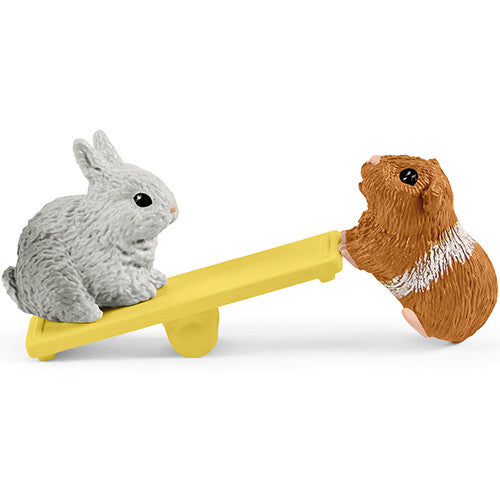 Detail van de Schleich speelset met een konijn en een cavia op een gele wip.