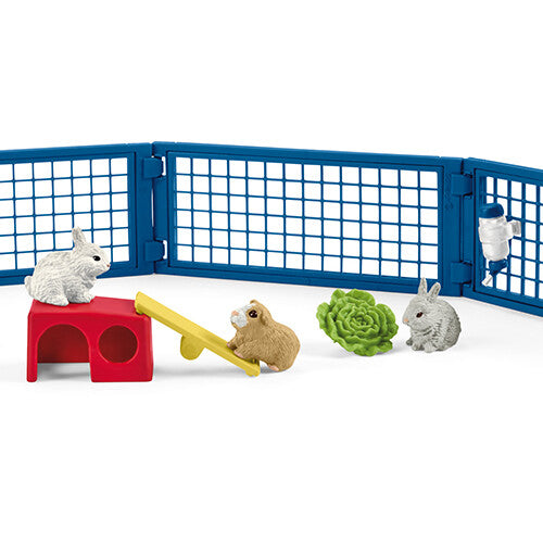 Schleich speelset met blauw hek, konijnen, cavia's, een rood huisje, een gele wip en een waterflesje.