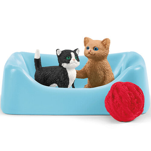 Twee Schleich kattenfiguren in een blauwe kattenmand met een rode bol wol.