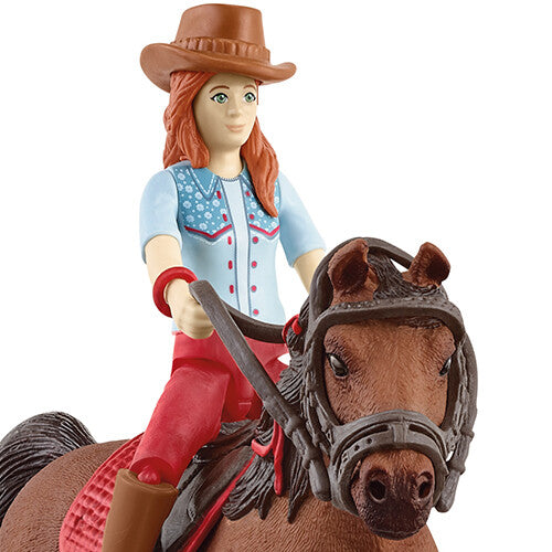 Detail van de Schleich speelgoedfiguur van een meisje met cowboyhoed op een bruin paard.