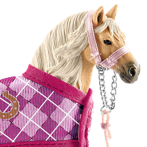 Close-up van het Schleich paardenfiguurtje met roze halster en geruite deken.
